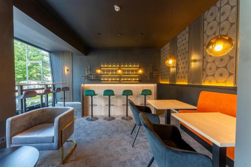 a restaurant with wooden tables and green chairs at JustStay Essen Hotel & Apartments in Essen