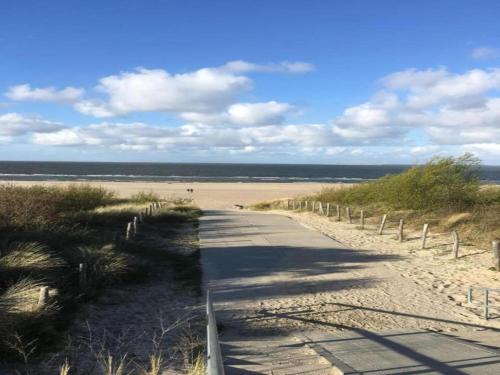 uma estrada de terra que leva a uma praia com uma cerca em Luxury apartment in Renesse with infrared sauna em Renesse
