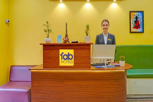 a woman standing at a reception desk with a laptop at FabHotel Martine's Residency - French Colony, 5 Mins from Rock Beach in Puducherry