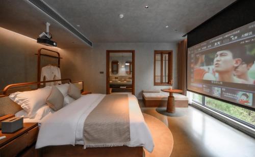 een slaapkamer met een groot bed en een groot scherm bij LongSen Valley Inn in Zhukeng