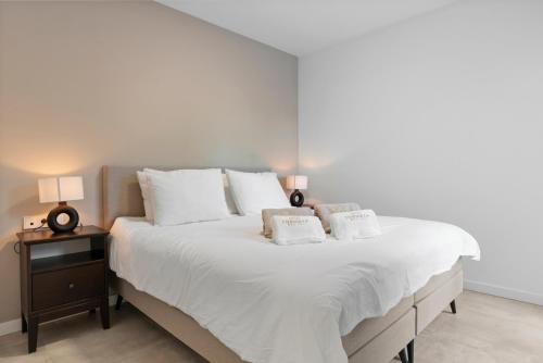 una camera da letto con un grande letto bianco con due cuscini di Luxury 3BR Garden Apartment Estepona a Estepona