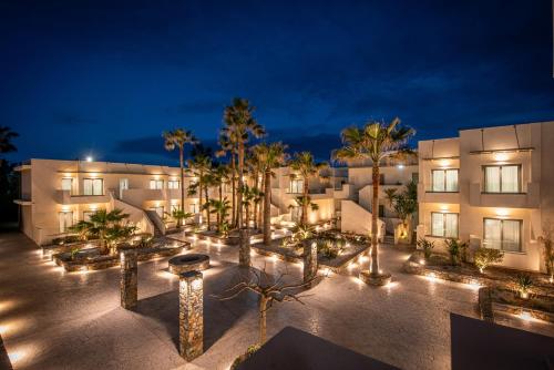 a building with a courtyard with palm trees and lights at Saint George Gournes Bay "by Checkin" Adults Only in Gournes