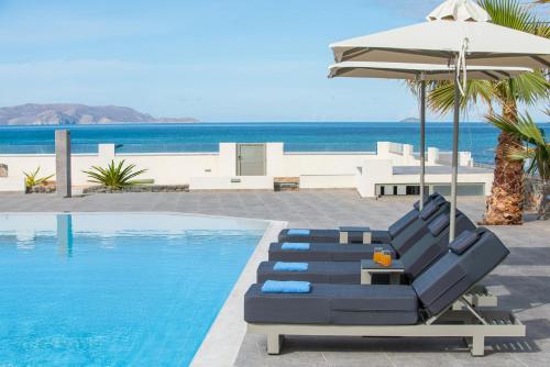 uma piscina com duas espreguiçadeiras e um guarda-sol em Saint George Gournes Bay em Goúrnai