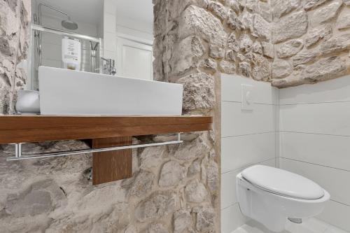 マカルスカにあるVilla Old Town Centre Makarska - Makarska Exklusivの石壁のバスルーム(白い洗面台付)