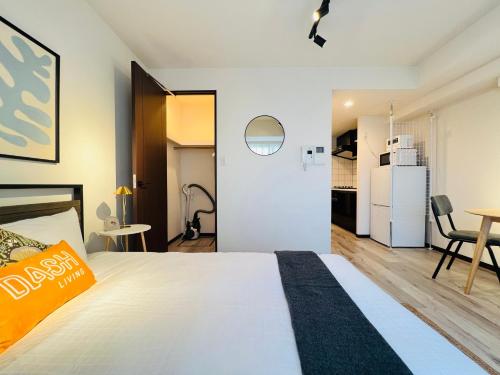 a bedroom with a bed and a kitchen with a refrigerator at Dash Living Ryogoku in Tokyo