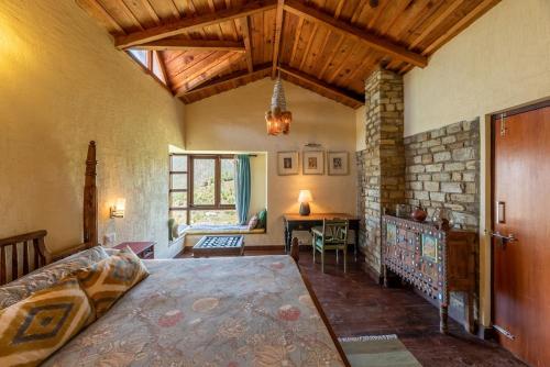 een slaapkamer met een bed en een tafel in een kamer bij Wild Thyme - Levitate at Ramgarh by Roamhome in Rāmgarh