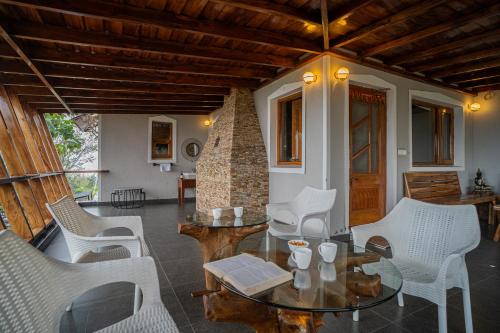 a living room with white chairs and a table at ELIVAAS Tapovan Estate 2-BHK With Kids Attic, Garden, Gazebo and Scenic Views in Bhowāli