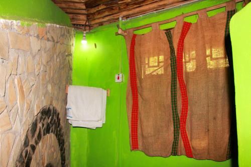 a green bathroom with a shower with red curtains at Songota Falls Lodge in Arusha