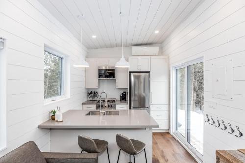 a white kitchen with a sink and two chairs at The Hideaway - Tiny House in Eugenia