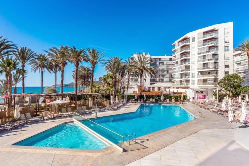 a swimming pool with palm trees and a building at Hotel Vibra Algarb in Playa d'en Bossa