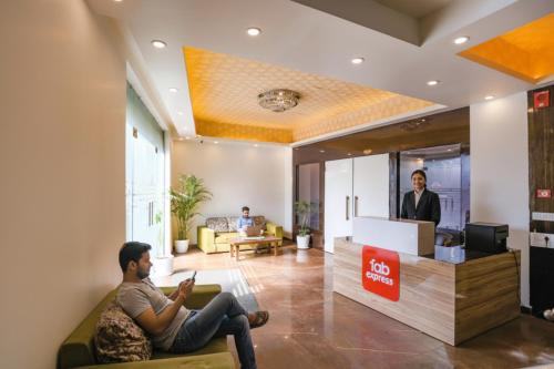 新德里Via Kapashera Residency Near IGI Airport New Delhi的一名男子坐在酒店大堂的沙发上。