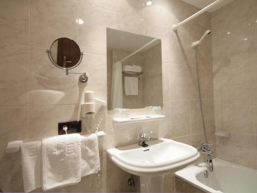 a white bathroom with a sink and a mirror at Hotel y Apartamentos Arias in Navia