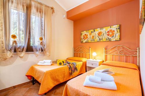 two beds in a room with orange walls at Villa Torre del Mare in Scopello