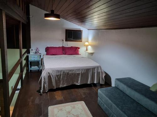 a bedroom with a bed with red pillows and a table at CASA em CAMBURI in São Sebastião