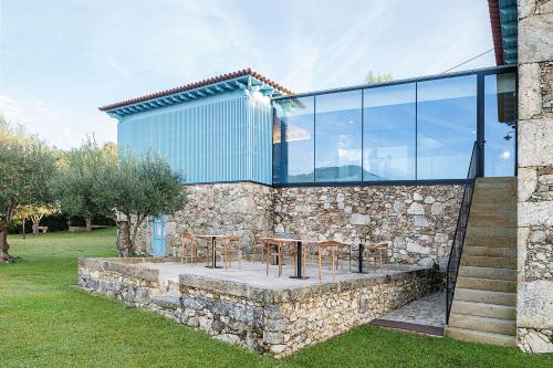 ポンテ・デ・リマにあるCapim Limão Country Houseの石の壁の上にテーブルと椅子が置かれた石造りの建物