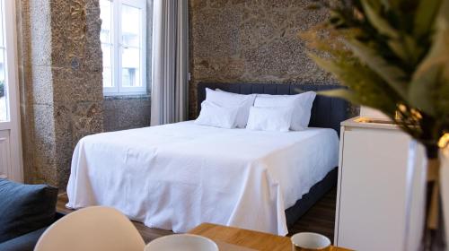 a bedroom with a bed with white sheets and pillows at D Maria Apartments in Vila Nova de Famalicão