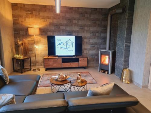 ein Wohnzimmer mit einem Sofa, einem TV und einem Kamin in der Unterkunft Eifel Dream Casa29 in Burbach