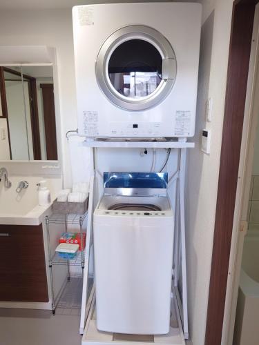 a washer and dryer in a bathroom with a sink at ペンションsakuraRIGHT in Motobu