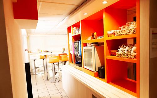 Una cocina con estantes rojos y amarillos y un mostrador. en Premiere Classe La Rochelle Nord - Puilboreau, en Puilboreau