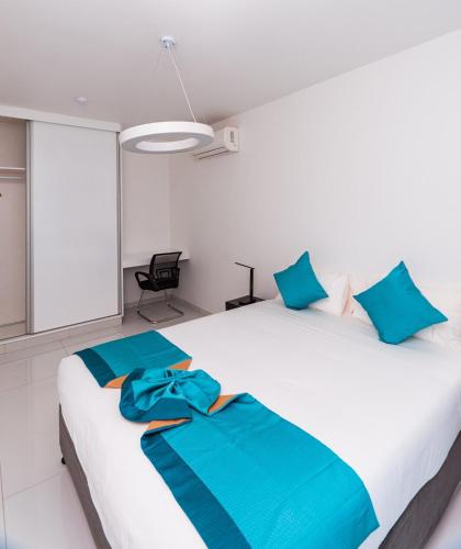 a bedroom with a large white bed with blue pillows at Golf View Apartments- AP2 in Maputo