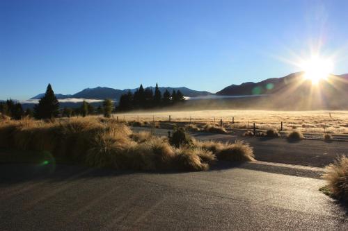 a road in a field with the sun in the sky at Sam's Place in Lake Tekapo