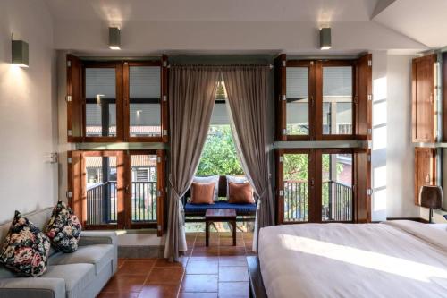 a bedroom with a bed and a couch and windows at Villa Pateh in Trang