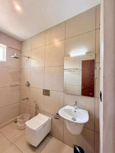 a white bathroom with a sink and a toilet at Vanaheim Resort in Vagamon