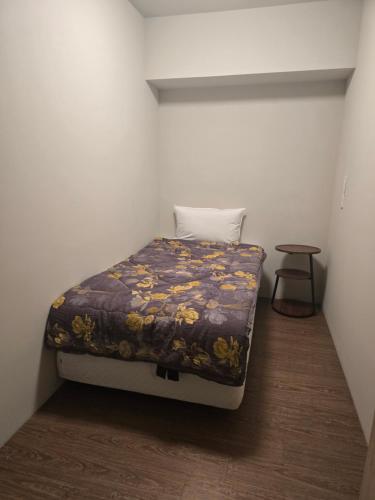 a small bed in a small room with a table at Hao Chi Tao Hotel in Kaohsiung