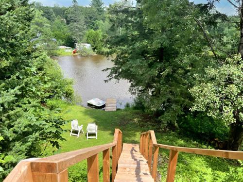 a wooden walkway leading to a lake with two chairs at Waterfront with Spa - Le Retro in Windsor