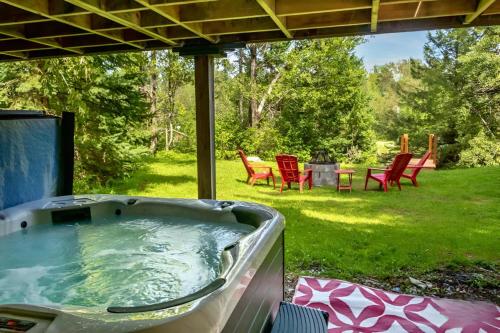 a hot tub in a yard with red chairs at Waterfront with Spa - Le Retro in Windsor