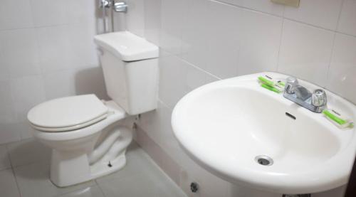 een badkamer met een wit toilet en een wastafel bij Hotel Latino in Panama-Stad