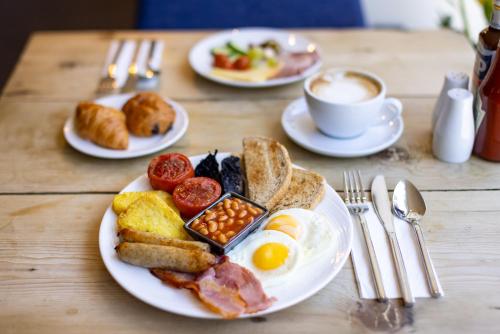 a table topped with plates of breakfast foods and a cup of coffee at Hotel Xanadu in London