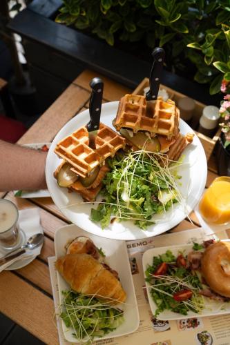 two plates of food on a table with waffles and salad at Hotel Holland House Old Town in Gdańsk