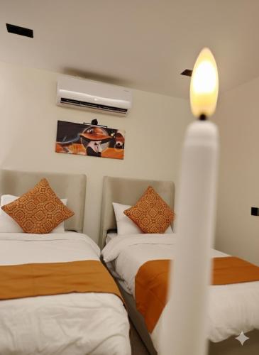 a bedroom with two beds and a light on the wall at غرفتين نوم مع صاله دخول ذاتي in Quai