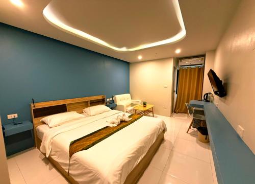 une chambre avec un grand lit avec un mur bleu dans l'établissement THE NICE, à Patong Beach
