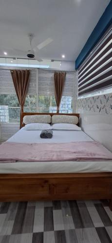 a bedroom with a large bed in a room with windows at Cloud Mist Inn YERCAUD in Yercaud