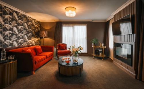 a living room with an orange couch and a tv at The Fairview Boutique Hotel in Killarney