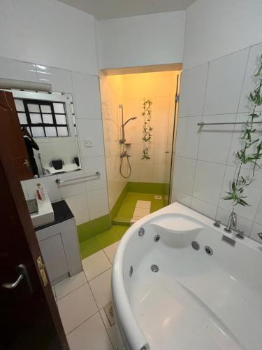 Cozy Two-Bed Retreat في نيروبي: حمام أبيض مع حوض استحمام ودش