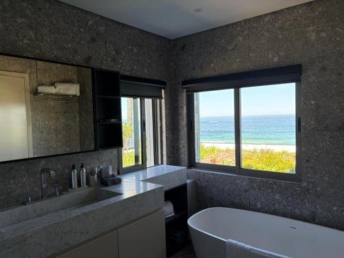 a bathroom with a tub and a view of the ocean at Nalu Villa in Cape Town