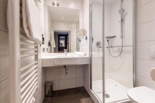 a white bathroom with a sink and a shower at Premier Inn Passau Weisser Hase in Passau