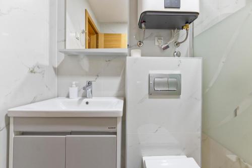 a white bathroom with a sink and a toilet at Apartman Vida Zlatibor in Zlatibor
