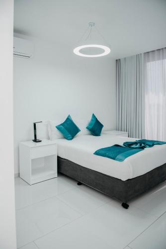 a white bedroom with a large bed with blue pillows at Golf View Apartment-AP4 in Maputo