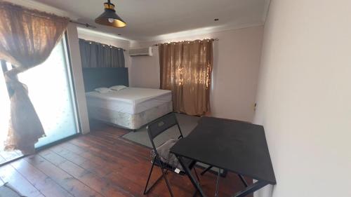 a bedroom with a bed and a desk and a table at Maun HideOut in Maun Airport