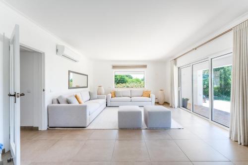 un soggiorno con mobili bianchi e ampie finestre di Villa Benjamin - Vale do Lobo a Vale do Lobo
