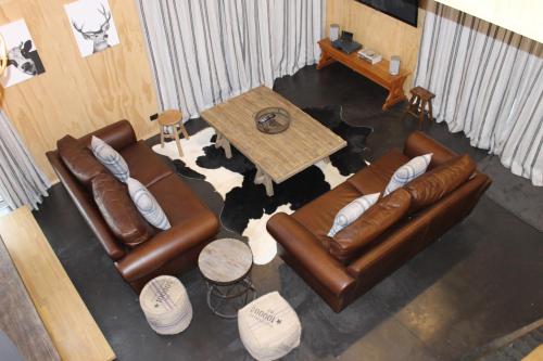 a living room with two leather couches and a table at Tractor Shed in Lake Tekapo