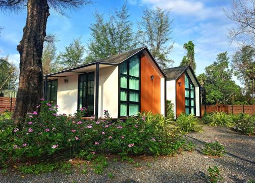 a house with windows and flowers in a yard at Seashell Family-555普吉岛木屋走几步到邦涛海滩看日落周边餐饮方便 in Bang Tao Beach