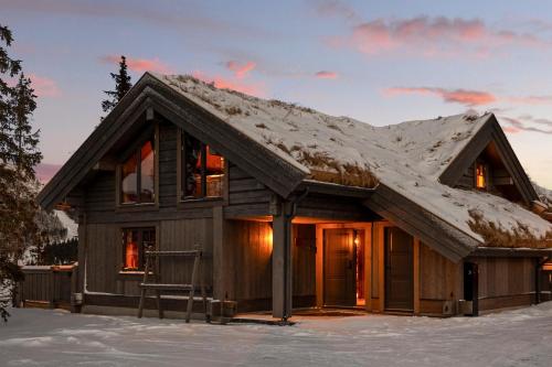una cabaña de troncos con nieve en el techo en Hyttekos Lodge, en Kvitfjell