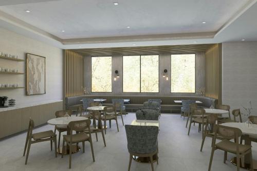 Un comedor con mesas y sillas y ventanas. en Residence Inn by Marriott Melville, en Melville