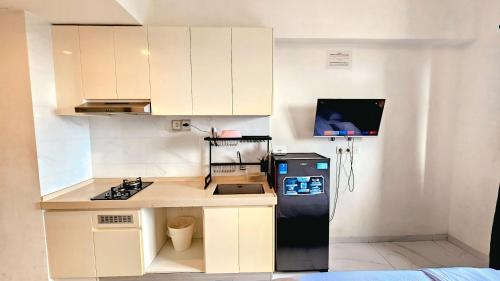 małą kuchnię z białymi szafkami i czarną lodówką w obiekcie Apartement Skyhouse Bsd TL26K By LiviRooms Tangerang w mieście Samporo