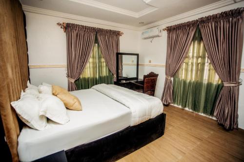 a bedroom with a large white bed in front of windows at A Luxury 3 bedroom bungalow in Owerri